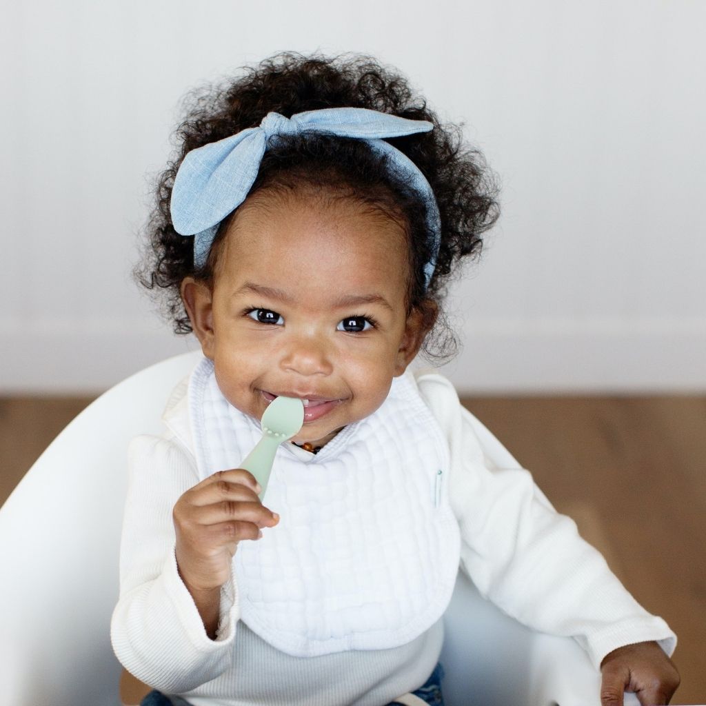 Baby girl self-feeding with EZPZ Tiny Spoon